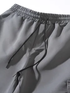 Close-up detail of grey cargo pants showing elastic waistband with black adjustable drawstring