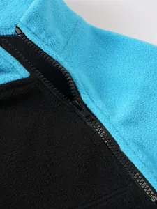 Detail eines schwarzen Reißverschlusses an einer blau-schwarzen Fleecejacke mit Stehkragen.