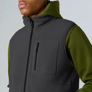 Close-up detail of dark grey polar fleece vest featuring a zipper pocket and stand collar.