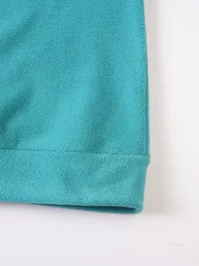 Close-up of the turquoise fleece sweatshirt hem showing soft texture and stitching
