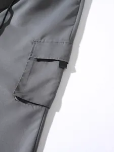 Detailed view of the large side flap pocket on grey cotton cargo joggers with drawstring.