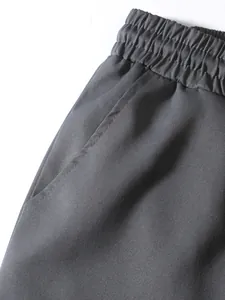 Macro detail view of grey men's cargo pants showing elastic waistband and side pocket.