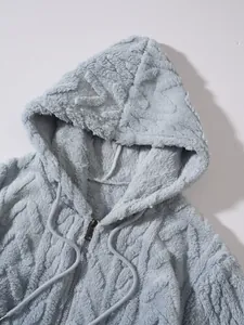 Detail van de zachte lichtblauwe pluche stof en kabelpatroon van een jas met capuchon.