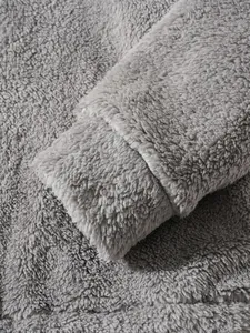 Close-up detail of a grey plush fleece jacket showing the soft fabric texture and ribbed cuff