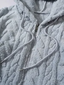 Detailopname van lichtblauwe fleece hoodie met zachte textuur en rits-detail.