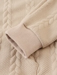Macro view of beige jacquard textured fabric and ribbed sleeve cuff on men's warm hoodie jacket