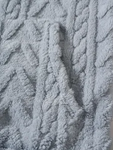 Gedetailleerde macro-opname van zachte lichtblauwe fleece stof met kabelgebreid patroon