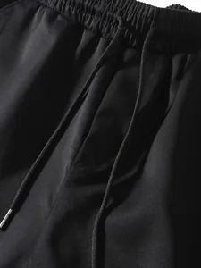Detail shot of men's black cargo pants showing the elastic waistband and drawstrings