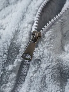 Detailopname van de metalen rits op een zachte lichtblauwe pluizige fleece jas