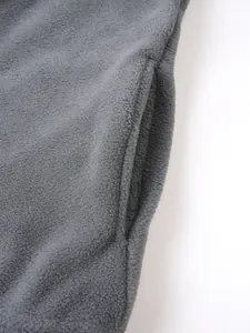 Detailansicht der grauen Fleece-Sweatshirt-Tasche und der warmen Stoffstruktur im Close-up.