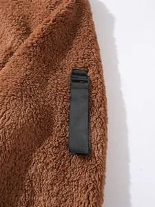 Close-up detail of a brown fuzzy fleece hoodie featuring a black decorative strap buckle