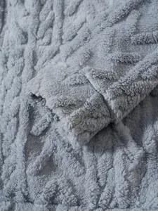 Detailopname van een zachte lichtblauwe fleece hoodie met kabelpatroon en knusse textuur