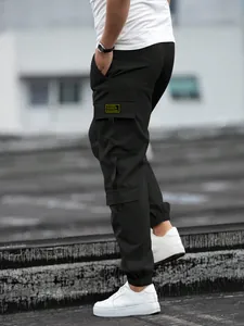 Side view of men's black cargo jogger pants with street style yellow pocket patch detail