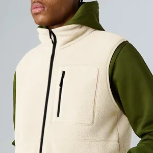 Close-up of men's cream sherpa fleece vest with black zipper and chest pocket detail