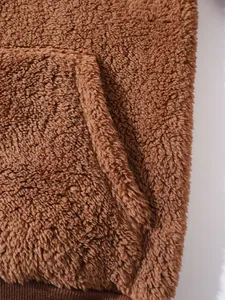 Macro close-up detail of soft brown plush fleece hoodie featuring kangaroo pocket texture