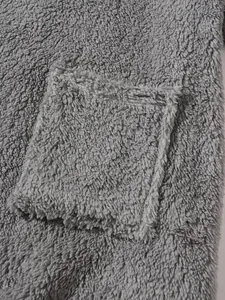 Close-up detail of the grey plush fleece fabric and front pocket on a sweatshirt