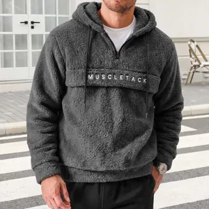 Men's charcoal gray plush fleece hoodie featuring MUSCLETACK chest print and drawstring.