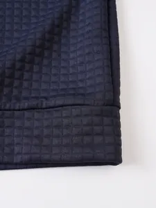 Detalle macro del tejido de punto gofrado con textura de cuadros azul oscuro de la sudadera.