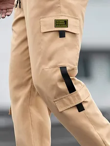 Detailed view of khaki cargo pants pocket with decorative black straps and label