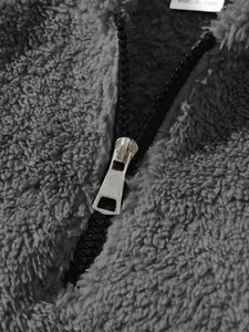 Close-up detail of the durable metal zipper puller on a soft grey plush fleece jacket texture