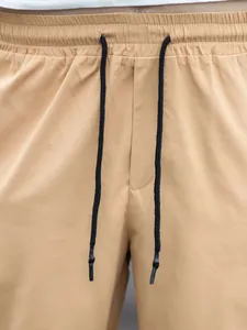 Close-up detail showing the elastic waistband and black drawstring on khaki men's cargo joggers