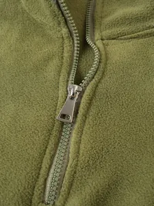 Nahaufnahme eines robusten Metallreißverschlusses an einem grünen Fleece-Sweatshirt