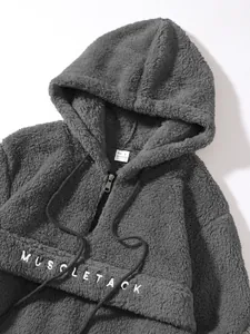 Detail view of a gray fleece hoodie featuring MUSCLE TACK embroidery and drawstring.