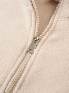 Detailansicht eines langlebigen Metallreißverschlusses am beigen Fleece-Sweatshirt