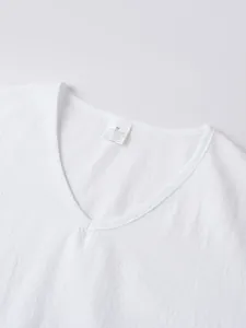Close-up detail showing the v-neckline and care label of a white linen men's shirt