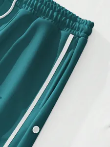 Close-up detail of men's teal casual pants featuring white side stripes and snap buttons