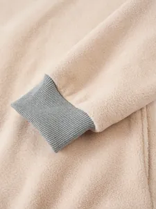 Detaillierte Nahaufnahme des grauen Rippbündchens und der beigen Fleece-Textur eines Herrenpullovers.