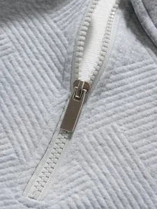Detailansicht des weißen Reißverschlusses und der grauen Textur des Polo-Shirts