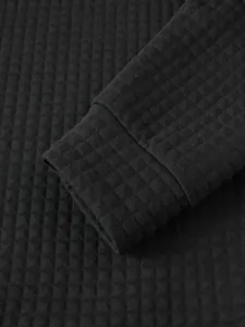Detalle de sudadera negra para hombre con textura de punto de gofre y puños acanalados