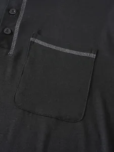 Détail de la poche de poitrine avec coutures contrastées sur un polo noir à manches longues.