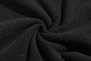 Detalle macro de tela polar negra suave y gruesa que muestra su textura densa y muy cálida