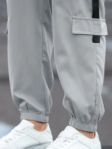 Close-up of men's grey cargo jogger pants with elastic cuffs and pocket detail