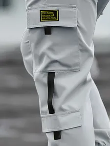 Close-up of cargo pocket detail on men's grey high-street joggers with text patch.