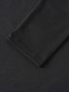 Gros plan d'un polo noir à manches longues montrant les coutures du poignet et le tissu