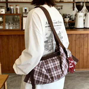 Gros plan d'un sac cabas en toile à carreaux vintage porté en bandoulière sous le bras