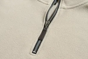Primer plano de sudadera de forro polar beige mostrando el detalle de cremallera y tela