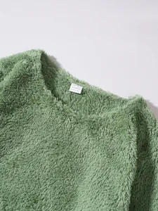 Detail of soft green fuzzy fleece sweatshirt showing fabric texture and neck label