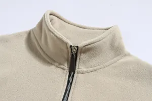 Primer plano del cuello alto y la cremallera de una chaqueta de forro polar beige para hombre.