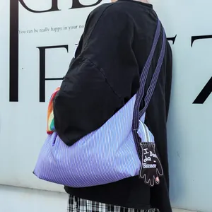 Vue détaillée d'un sac fourre-tout en toile à rayures bleues avec son pendentif gant original