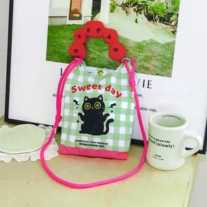 Detailed view of cartoon cat mini crossbody bag with green gingham and red wavy handle.
