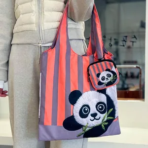 Gros plan de la broderie panda sur un sac cabas rayé rose et violet réutilisable.