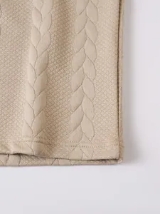 Close-up of beige jacquard knit fabric texture with cable and diamond weave patterns