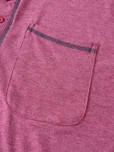 Détail macro de la poche de poitrine avec coutures contrastées sur un polo rouge chiné