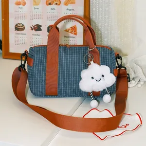 Borsa bowling a quadretti blu con tracolla marrone e ciondolo a forma di nuvola bianca.
