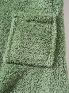 Close-up detail of soft sage green sherpa fleece fabric showing pocket texture and quality