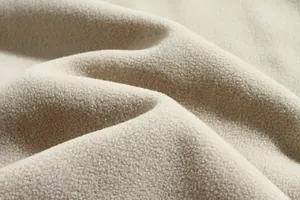 Detalle macro de la suave textura del tejido de forro polar crema para chaqueta de invierno